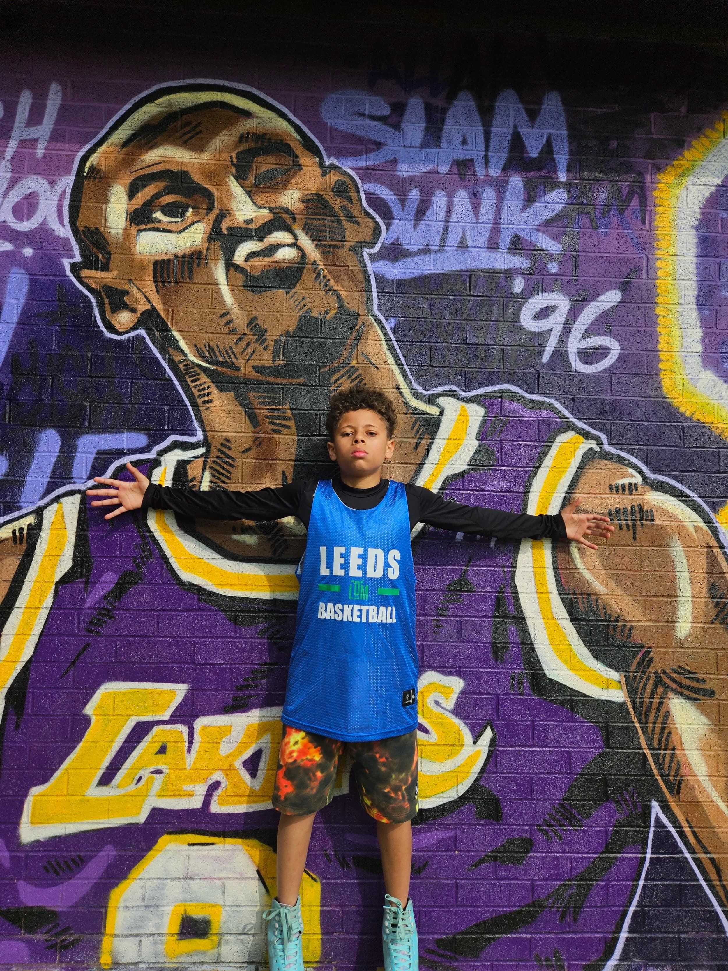 A young Leeds LDM Basketball player standing in front of a colourful mural